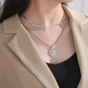 Detail of silver double layered chain necklace with religious figure pendant on model