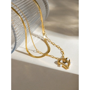 Close-up of 18k gold-plated heart pendant with embedded pearls on a double-layer chain