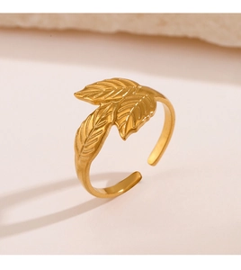 Detail eines verstellbaren goldenen Edelstahlrings mit Blattdesign auf Steinhintergrund