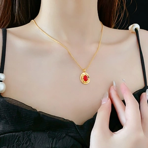 Close-up of a vintage oval red pendant with gold textured edges on a gold chain