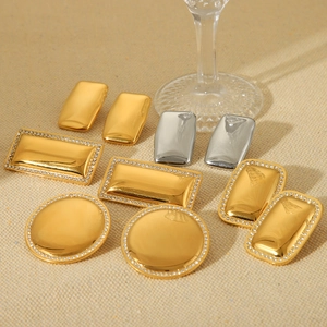 Polished 18K gold and silver geometric earrings with crystals on beige fabric
