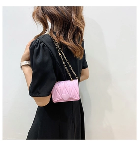 Detail of pink heart-shaped mini chain bag with quilted texture on female model