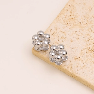 Polished silver floral earrings featured on a textured beige stone surface