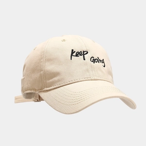 Beige cotton baseball cap with black Keep Going embroidery and adjustable strap