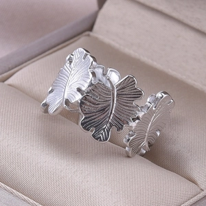 Macro shot of silver stainless steel ring featuring three detailed leaf motifs on a jewelry box