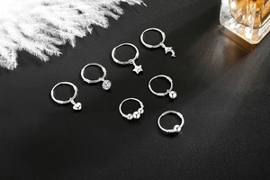 Close-up of s999 silver hoop earrings set with heart, star and moon charms on black background