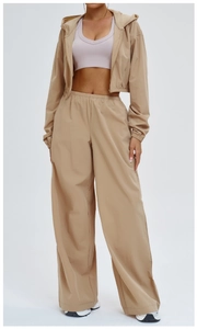 Detail of khaki windproof hooded sports jacket and wide-leg pants on model with white background