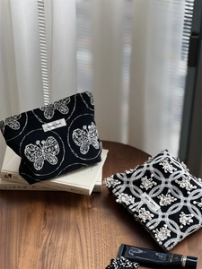 Detailed close-up of butterfly embroidery on black cotton linen fabric makeup bags