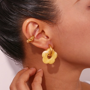 Close-up of model wearing 18K gold-plated flower charm earring and spiral ear cuff