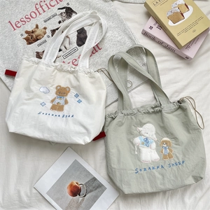 Detail of drawstring canvas tote bags featuring cute bear and sheep embroidery accents