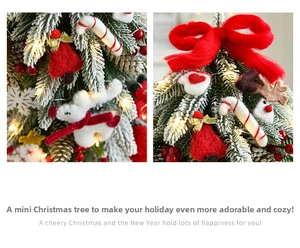 Close-up of mini Christmas tree with warm LED lights, felt reindeer and bell ornaments