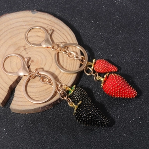 Close-up of red and black strawberry keychains with textured finish and golden clips