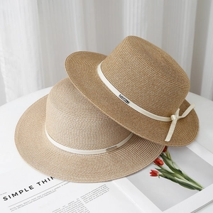 Detail of high-quality raffia straw hats showing fine weave texture and bow accents