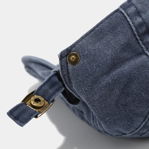 Gros plan sur la boucle rétro en laiton et la texture en denim bleu délavé de la casquette