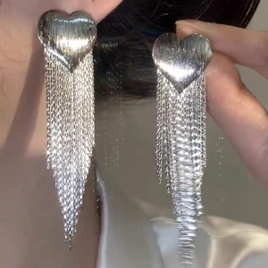 Close-up of silver metal heart studs with long tassel chains featuring brushed texture