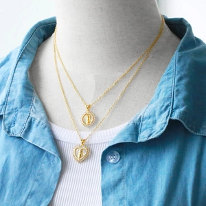 Detail of layered gold necklaces featuring Madonna pendants with sparkling zircon borders