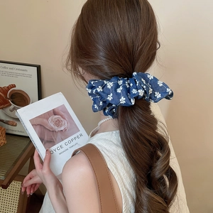 Detail of dark blue floral scrunchie worn on ponytail with elegant fabric texture