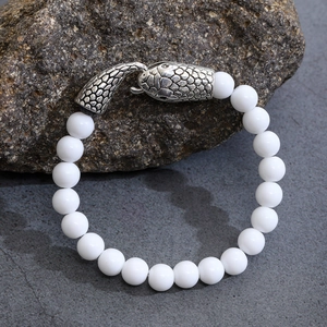 Dettaglio della chiusura in metallo a testa di serpente e bracciale di turchese bianco