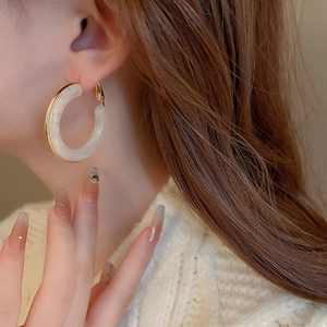 Close-up of vintage resin hoop earring with gold plating on a model's ear