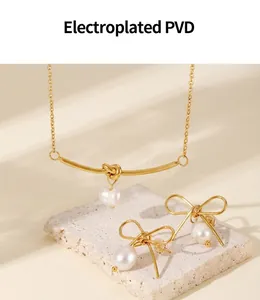Detail view of PVD gold plated bow earrings and pearl necklace on a stone pedestal