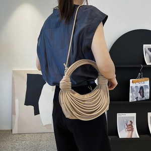 Chic beige knotted rope handbag with crescent silhouette worn by female model
