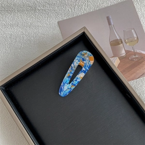 Close-up of teardrop hair clips with blue and yellow marble texture on a display tray