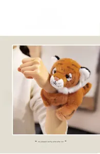 Plush orange tiger snap bracelet toy worn on a wrist showing fuzzy texture and stripe pattern