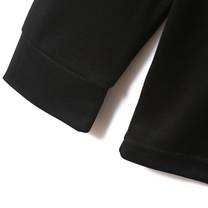 Detailed close-up of the black knit cuffs and hem stitching on a slim-fit polo shirt