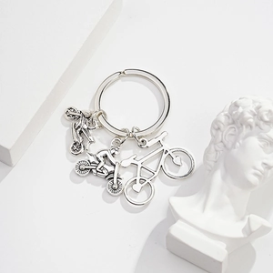 Detailed close-up of silver metal keychain with three miniature bicycle charms on white background