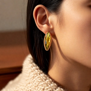 Close-up of elegant marquise amber crystal earrings with gold beaded trim on a model