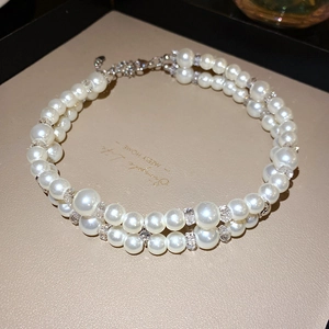 Close-up of double-layer white pearl necklace with crystal beads and lobster clasp detail