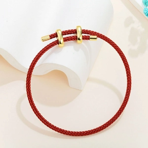 Detailed close-up of woven red string bracelet with adjustable gold metal fastener buckle