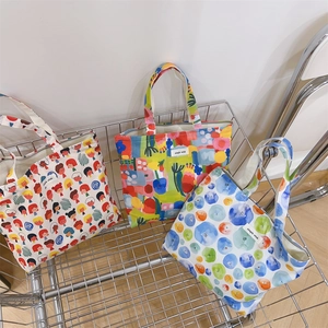 Detailed view of canvas tote bags with various colorful prints in a metal cart storage