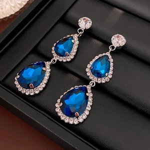 Macro shot of blue teardrop crystal earrings with sparkling rhinestones on black display