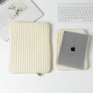 Vertical quilted laptop sleeve set in cream white with soft padded texture and zippers