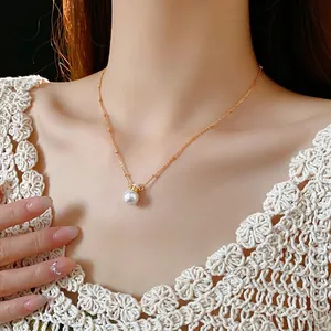 Elegant gold chain necklace featuring a single large white pearl pendant on a model