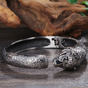 Détail du bracelet tête d'ours en acier inoxydable gris foncé sur bois rustique