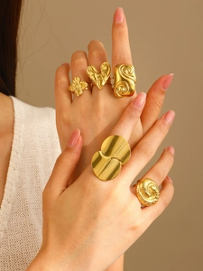 Detailed close-up of chunky gold floral and heart rings on fingers in a vintage style