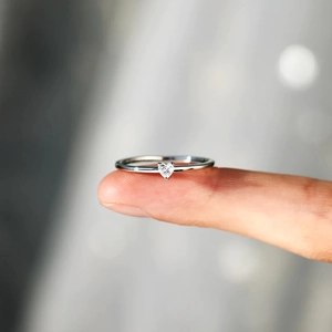 Close-up of minimalist S925 sterling silver ring with small heart-shaped zircon on finger