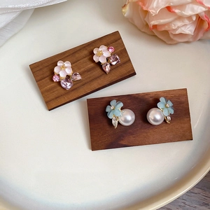 Close-up of floral crystal earrings with faux pearls on an elegant wooden display stand