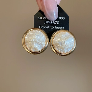 Dettaglio macro di orecchini a cuore in perla placcati oro 16K su cartoncino