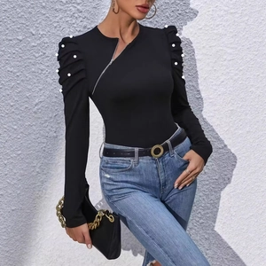 Detail of elegant black slim top featuring pearl-studded puff sleeves and a side zipper