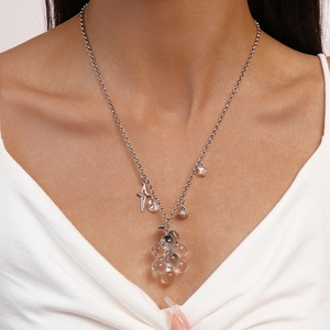 Close-up of silver necklace featuring diamond-set star and clear grape bead pendants