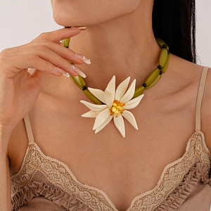 Detail view of a green bead necklace featuring a large white resin flower pendant on model