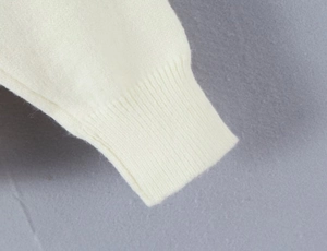 Detailed close-up of thick ribbed knit texture on a white cardigan sleeve cuff