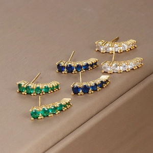 Macro detail of gold stud earrings with round blue, green and clear gemstones