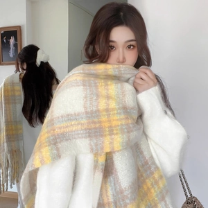 Close-up of soft yellow and white checkered knit scarf featuring long fringe tassels