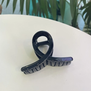Pince à cheveux torsadée noire classique avec finition brillante sur surface blanche