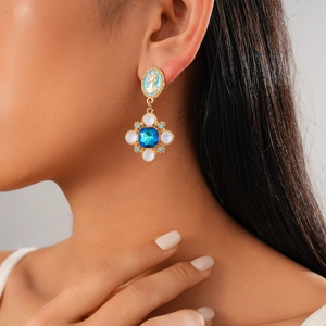Close-up of vintage cameo pendant earring featuring blue resin and opal-like stones