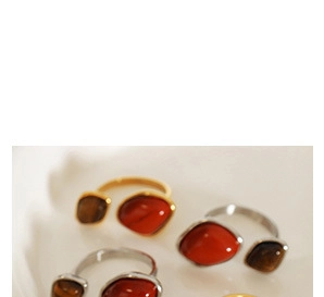 Detalle de anillos abiertos de oro y plata con ágata roja e incrustación de ojo de tigre